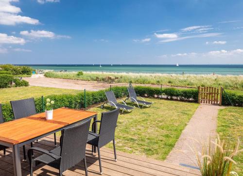 einen Holztisch und Stühle auf einer Terrasse mit Strand in der Unterkunft Ocean 4 in Rettin
