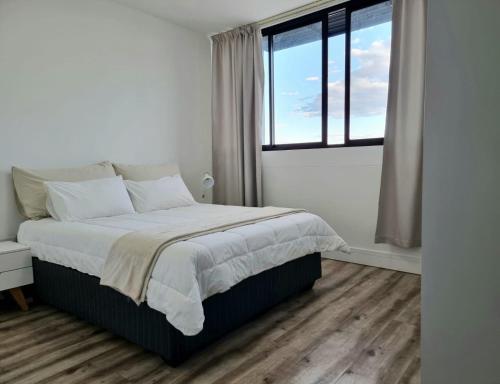 a white bedroom with a large bed and a window at Mary-B Contemporary Apartment in Windhoek