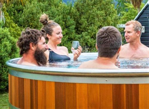 eine Gruppe von Personen in einem Whirlpool mit einem Glas Wein in der Unterkunft Heritage Log Cabin and Garden w Outdoor Hot Tub in Medlow Bath