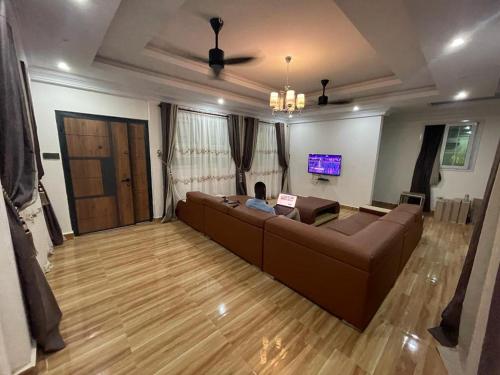 a living room with a brown couch and a tv at THE GREEN CONDO in Elmina