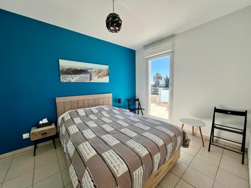 une chambre avec un lit et un mur bleu dans l'établissement Calypso, appartement Vue mer, à La Ciotat