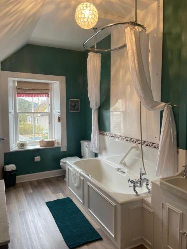 a green bathroom with a tub and a window at Clint Lodge in Melrose