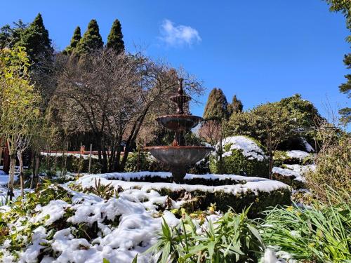 a fountain in a garden covered in snow at Heritage Log Cabin and Garden w Outdoor Hot Tub in Medlow Bath