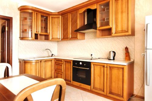 a kitchen with wooden cabinets and a black appliance at Apartment in Complex Korona on Knyazhyi Zaton 21 in Kyiv