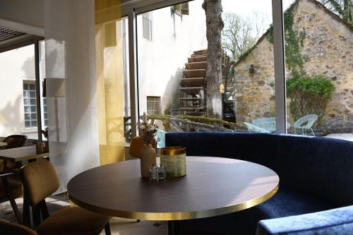 mesa y sillas en una habitación con ventana en Le Moulin Des Ruats, en Avallon