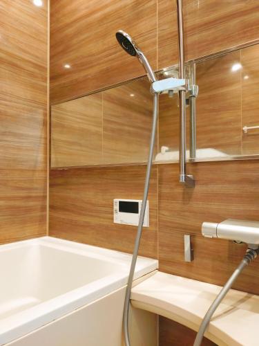 a shower in a bathroom with wooden walls and a bathtub at 15min to Haneda Airport - Homies House Kamata for up to 9 guests in Tokyo
