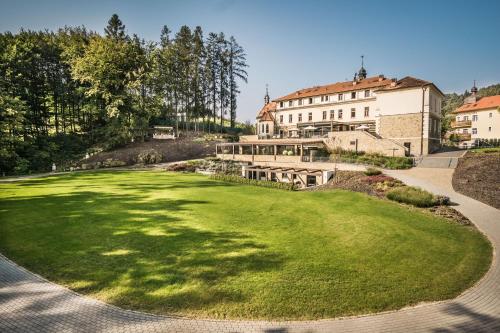 a green yard with a building in the background at Wellness & spa hotel Augustiniánský dům in Luhačovice