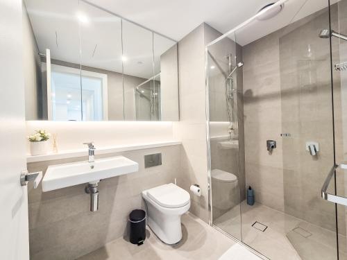 a bathroom with a toilet and a sink and a shower at Hamptons Style 2BR & kid room w view in Olympic Park in Sydney