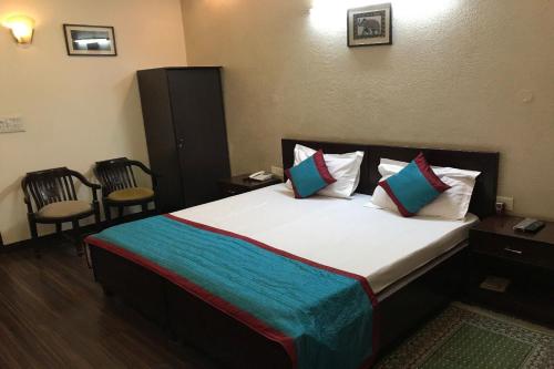 a large bed in a room with two chairs at OYO Vatika in Gurgaon