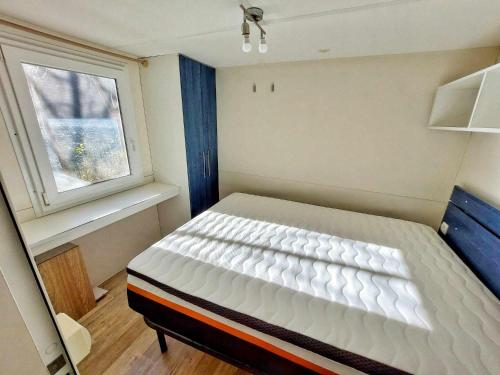 a small bedroom with a white bed and a window at Villaggio Turistico Il Lago Dorato in Carlazzo