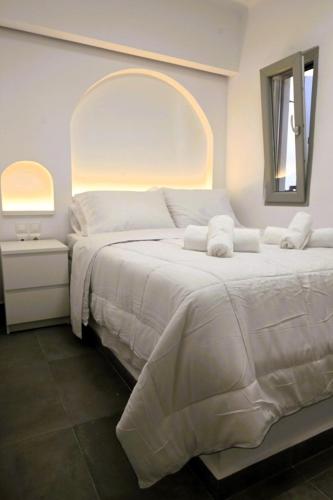a bedroom with a large white bed with a mirror at Bluewave Lux house in Ornos