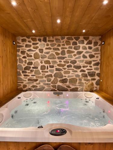 a large jacuzzi tub with a stone wall at Hotel Riva Sport & Wellness in Vione