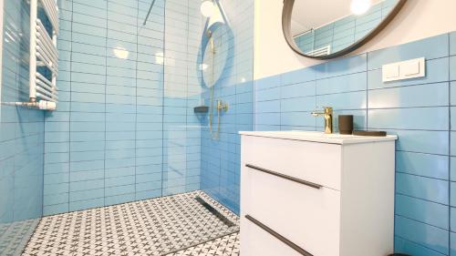 een blauw betegelde badkamer met een wastafel en een spiegel bij Apartamenty Sun & Snow Villa Verona in Mielno