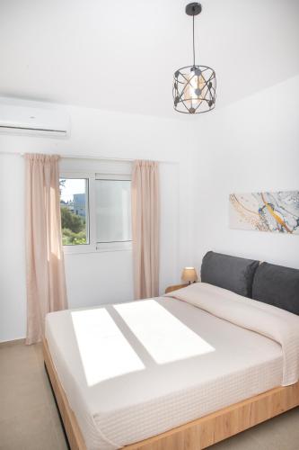 a white bedroom with a bed and a window at Etheria Comfort House in Kos