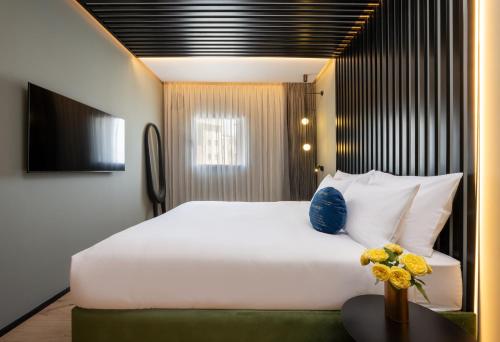 Un dormitorio con una gran cama blanca y una mesa en Hotel Poli Urban, en Tel Aviv