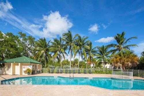 a swimming pool with palm trees in the background at Tortuga Suite at Sunrise Suites Resort - Heated Pool, Hot Tub & Free Parking in Key West