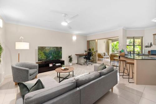 a living room with a couch and a table at Coastal Bliss - Cairns 9 Pools BBQ & Gym in Westcourt