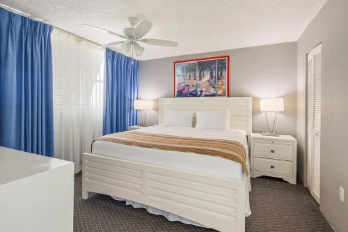 Schlafzimmer mit einem weißen Bett und blauen Vorhängen in der Unterkunft The Grand Turk by Brightwild-Sunset View & Pool in Key West
