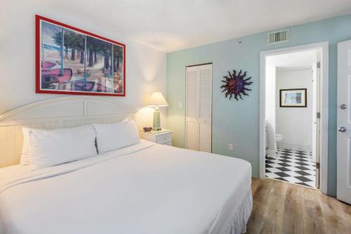 ein Schlafzimmer mit einem weißen Bett und einem Gemälde an der Wand in der Unterkunft The Samana Cay by Brightwild-Private Balcony in Key West