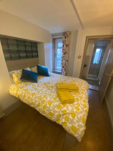 een slaapkamer met een bed met gele lakens en blauwe kussens bij Quiet cosy 1 bedroom apartment Carrington F1 in Nottingham