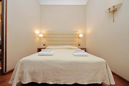 um quarto com uma cama branca com duas toalhas em Domus Maggiore em Roma