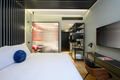 a bedroom with a bed and a desk and a tv at Hotel Poli Urban in Tel Aviv