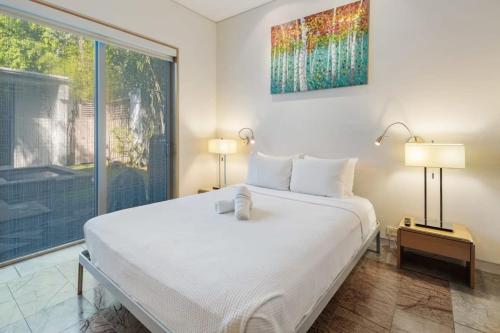 a bedroom with a white bed and a large window at Contra House by Brightwild-Luxury Home With Pool in Key West