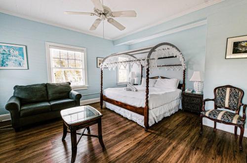 a bedroom with a canopy bed and a chair at Deluxe King with Balcony by Brightwild- at James House with Parking! in Key West