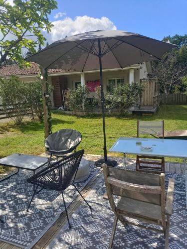a table and chairs and an umbrella in a yard at Chambre d'Hôtes Les Macarons de Tata in Sainte-Eulalie