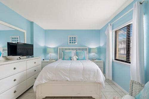 a blue bedroom with a bed and a television at Ocean Front Suite! Sunglow Resort 101 by Brightwild in Daytona Beach Shores