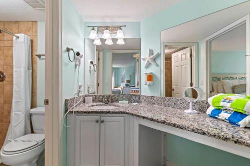 a bathroom with a sink and a toilet and a mirror at Ocean Front Penthouse with Incredible Views! Sunglow Resort 1003 by Brightwild in Daytona Beach Shores