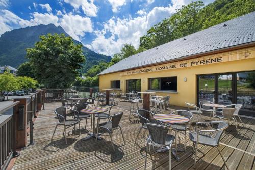 a deck with chairs and tables on a building at Domaine de Pyrène in Cauterets