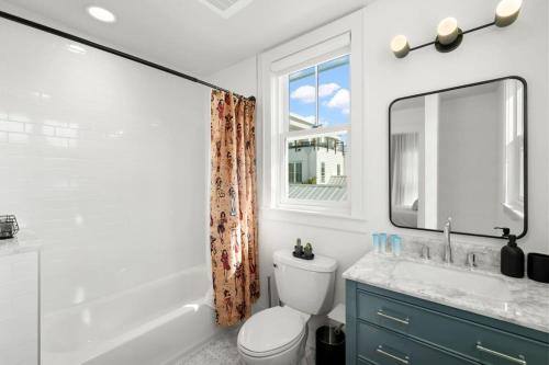 a bathroom with a toilet and a sink and a mirror at Casa Romeo - Luxury Ybor Apt, Steps to 7th Ave in Tampa