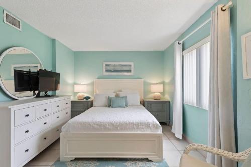 ein blaues Schlafzimmer mit einem Bett und einem Spiegel in der Unterkunft Aquamarine Suite at Sunglow Resort by Brightwild in Daytona Beach Shores