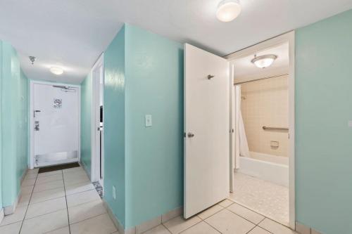 Aquamarine Suite at Sunglow Resort by Brightwild في Daytona Beach Shores: مدخل مع جدران زرقاء وحمام مع حوض استحمام