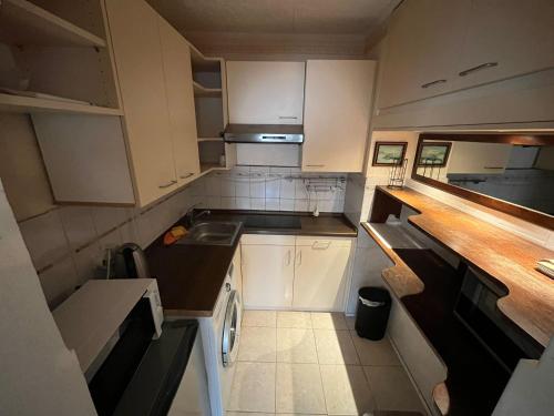 een kleine keuken met witte kasten en een wastafel bij Studio Apartment mit Balkon in Neumünster