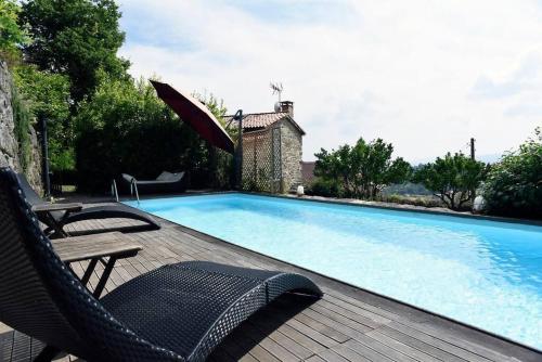 uma piscina com duas cadeiras e um guarda-sol em Casa de Afora Casa con piscina y jacuzzi privados em Santiago de Compostela