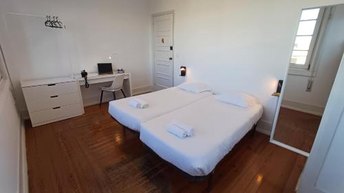 a white bedroom with a bed and a desk at HI Coimbra - Pousada de Juventude in Coimbra