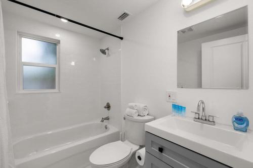 a white bathroom with a toilet and a sink at Casa Padrón - Gorgeous Home, Steps to 7th Ave in Tampa