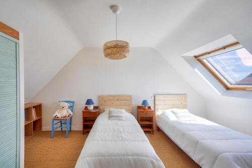 a attic bedroom with two beds and a window at Vue mer ! À 200m de la plage, maison pour 9 in Plovan