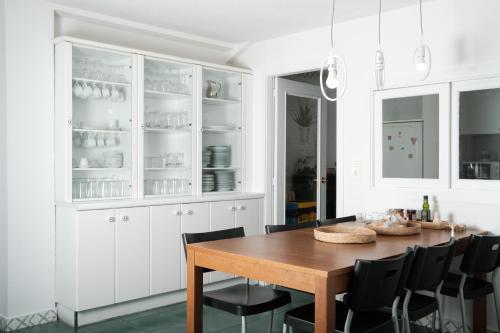 a white kitchen with a wooden table and black chairs at HOSTEL Rua 35 in León