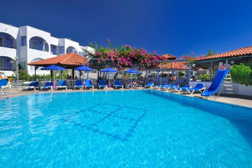una gran piscina con sillas y sombrillas azules en Kolymbia Sun en Kolimbia