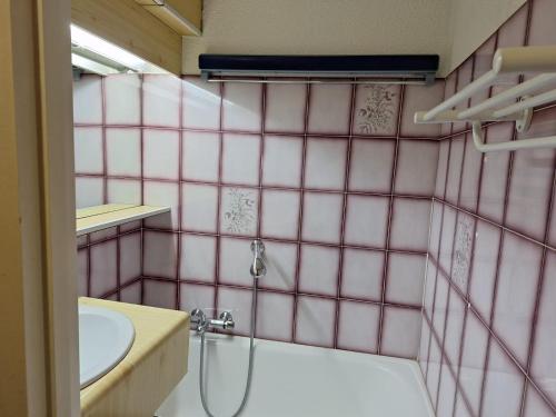 ein rosa gefliestes Bad mit einer Dusche und einem Waschbecken in der Unterkunft Studio à la montagne - Portes du Soleil in Abondance