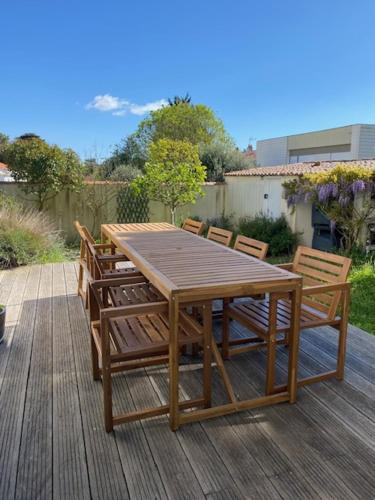 une table et des chaises en bois sur une terrasse en bois dans l'établissement MAISON CENTRE VILLE AVEC JARDIN , TERRASSE, et GARAGE VELOS, à La Rochelle