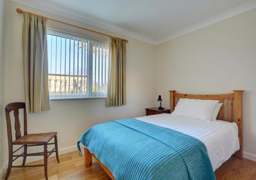 a bedroom with a bed and a chair and a window at Oak Tree Cottage in Old Buckenham