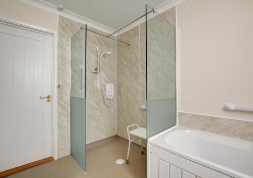 a bathroom with a shower with a glass door at Oak Tree Cottage in Old Buckenham