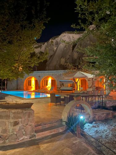a patio with a table and a swimming pool at night at Seven Rock Cave Hotel in Goreme