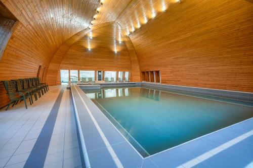 a swimming pool in a building with a wooden wall at Hunguest Helios Hévíz in Hévíz