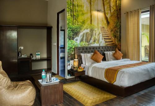 a bedroom with a bed and a painting of a waterfall at De Floresta Resort in Rāmnagar