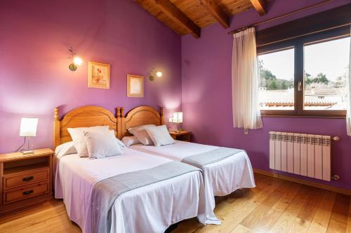 two beds in a bedroom with purple walls at Casa rural playa nves002r in Naves